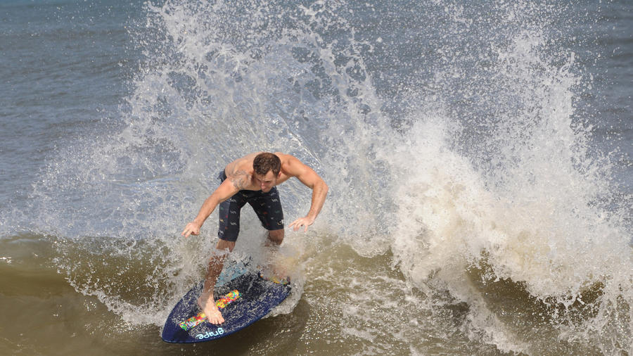 Elliot MacGuire from Rehoboth Beach, skim boards into the waves in Rehoboth Beach. (Kristin Roberts, Baltimore Sun)